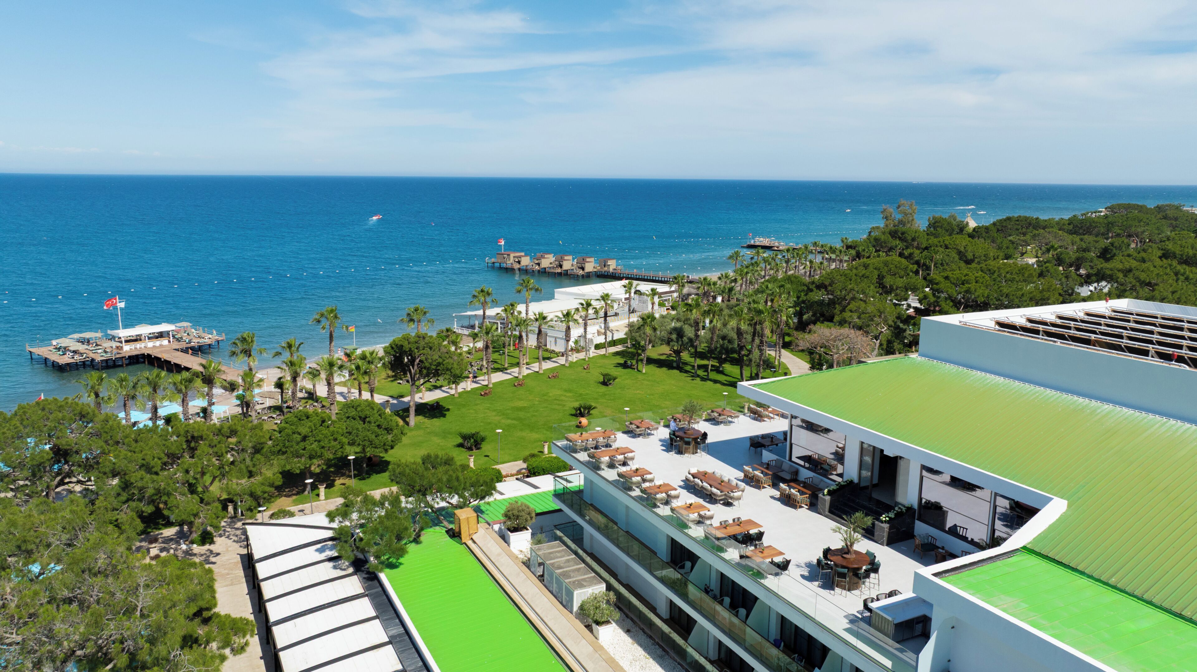 Un hotel sulla costa con terrazza sul tetto, un molo e vista mare.
