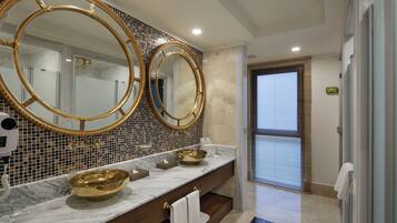 A bathroom with two large gold-framed mirrors, a marble countertop, and a gold bowl sink.