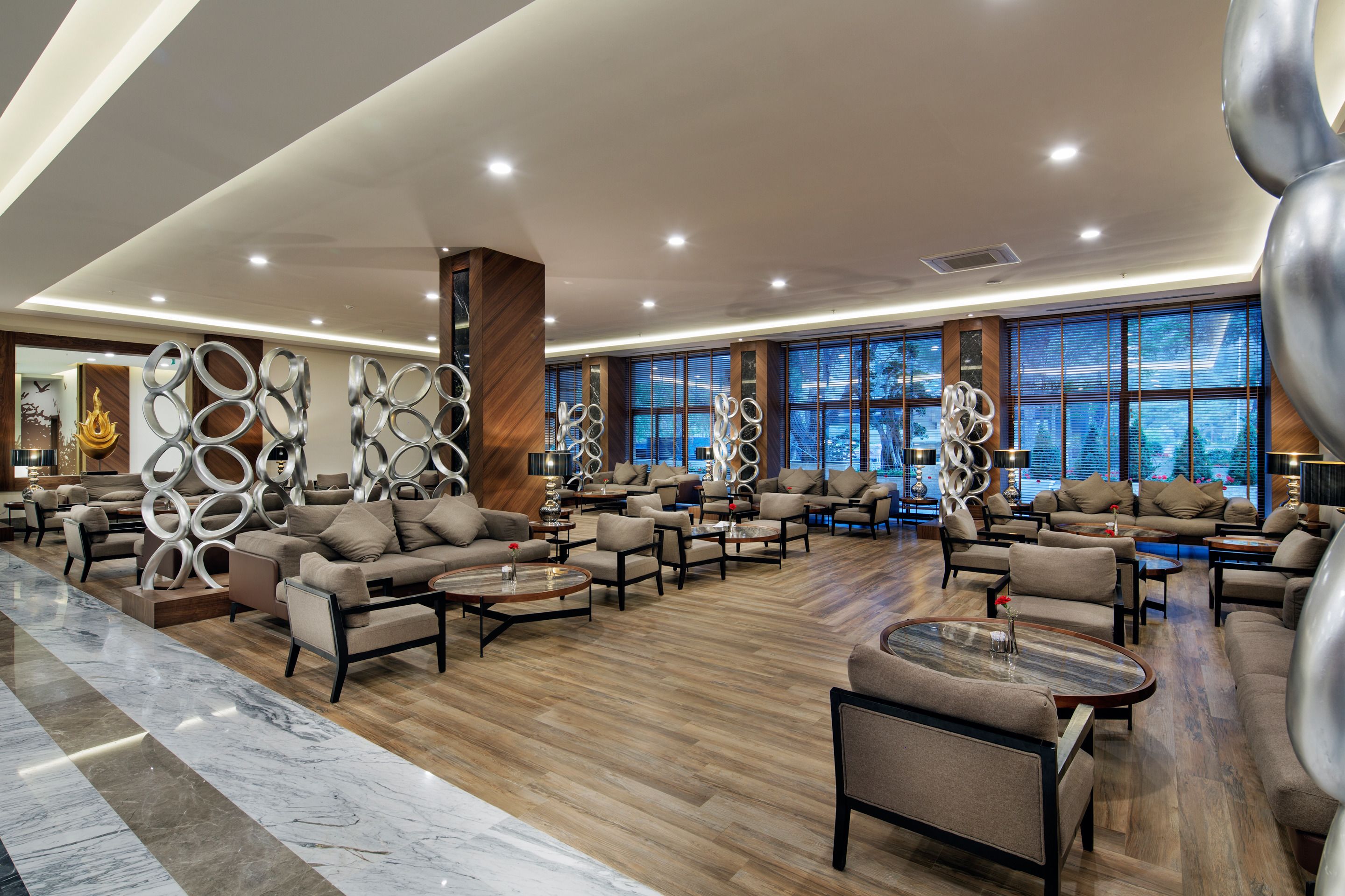 A spacious lobby with multiple seating areas, large windows, and a modern design.
