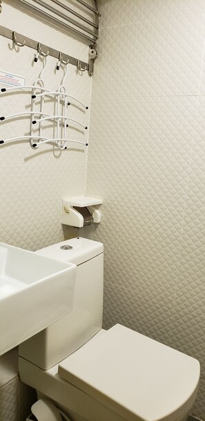 A bathroom with a white sink, toilet, and a hand dryer mounted on the wall.
