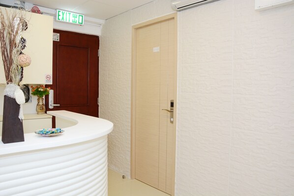 A reception area with a white counter, a wooden door, and an exit sign.