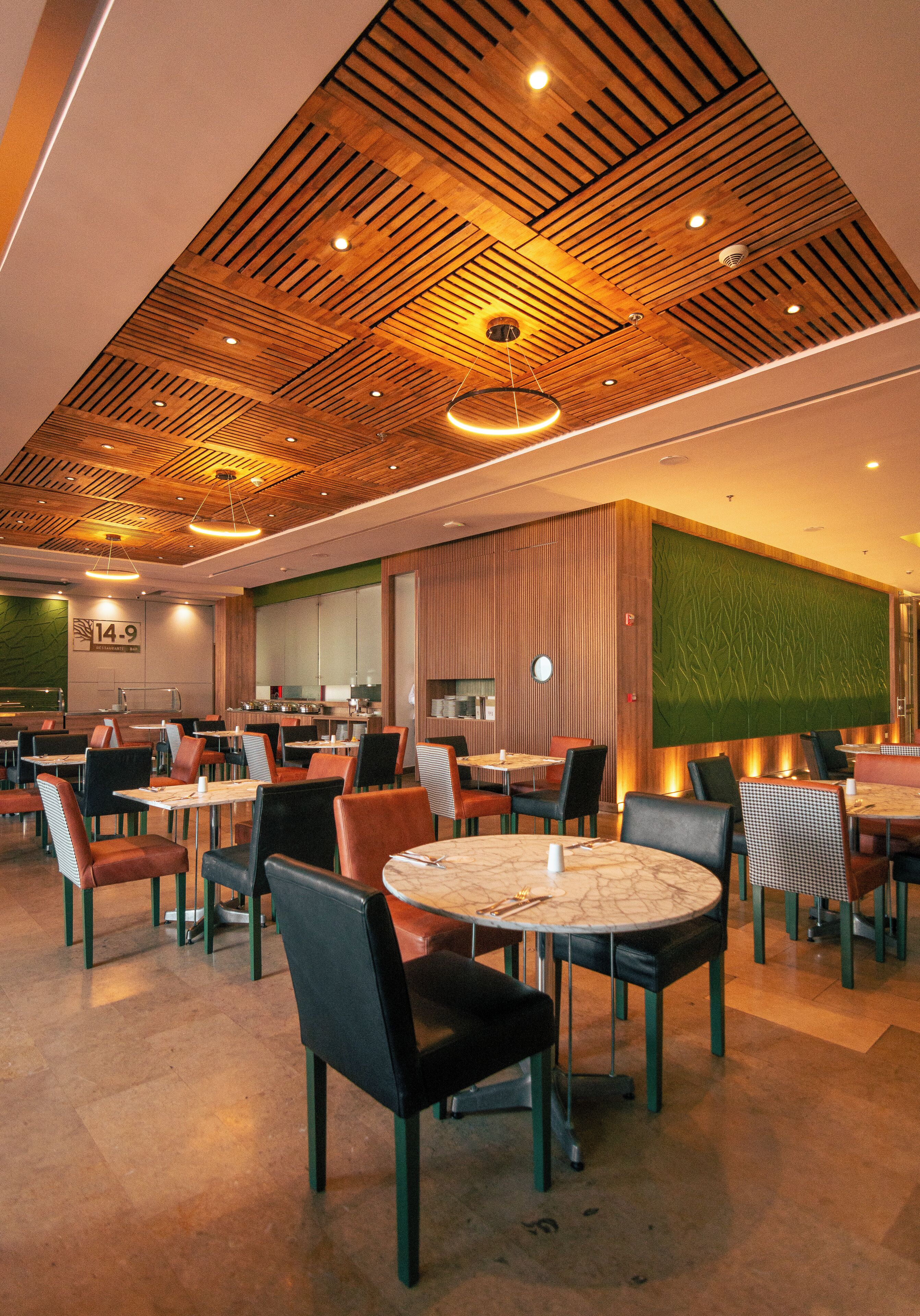 A modern dining area with wooden ceiling panels, round tables, and chairs.