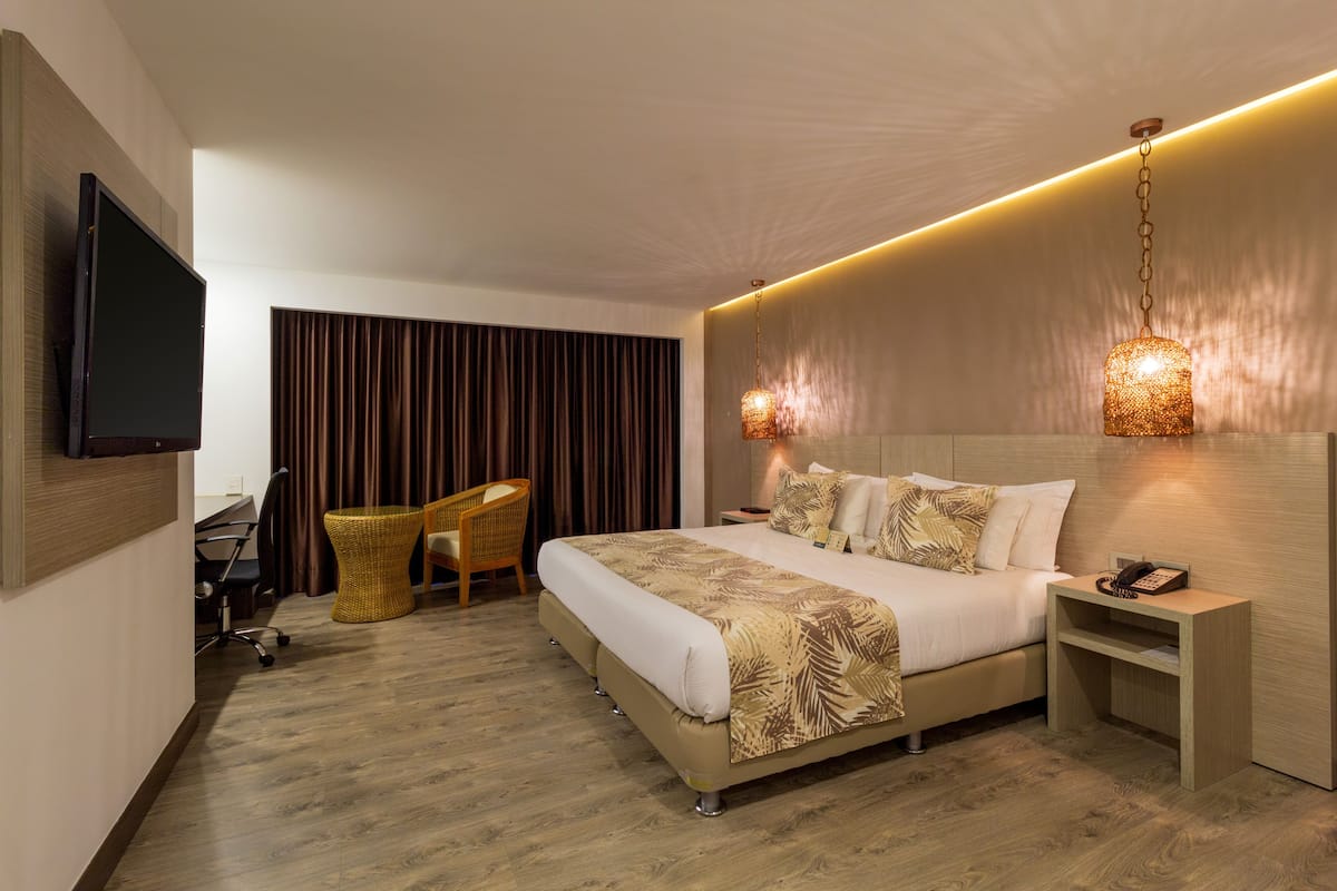 Una habitación de hotel moderna con una cama grande, un escritorio, una silla y un televisor.