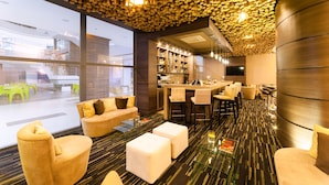 A modern hotel lobby with a bar area, seating, and a unique ceiling design. - Hotel Mocawa Plaza Armenia (Armenia)