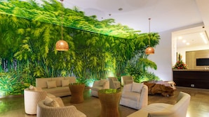 Un hall con una exuberante pared verde, muebles modernos y un televisor plano grande.