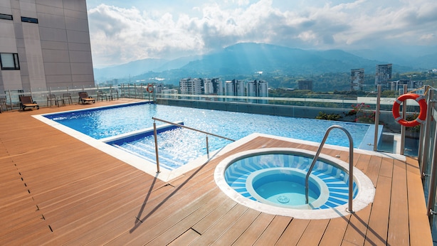 Una piscina en la azotea con vistas a montañas y edificios.