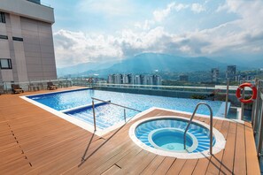 Una piscina en la azotea con vistas a montañas y edificios.