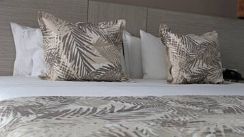 A bed with a patterned bedspread and multiple pillows, including a large one with a leaf design.