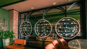 Un interior moderno con tres estantes circulares que exhiben botellas de vino, suelo de madera y asientos de cuero color naranja.