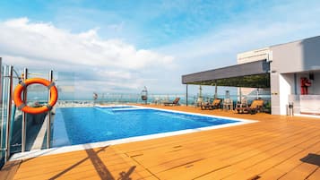 Una piscina al aire libre, sillones reclinables de piscina