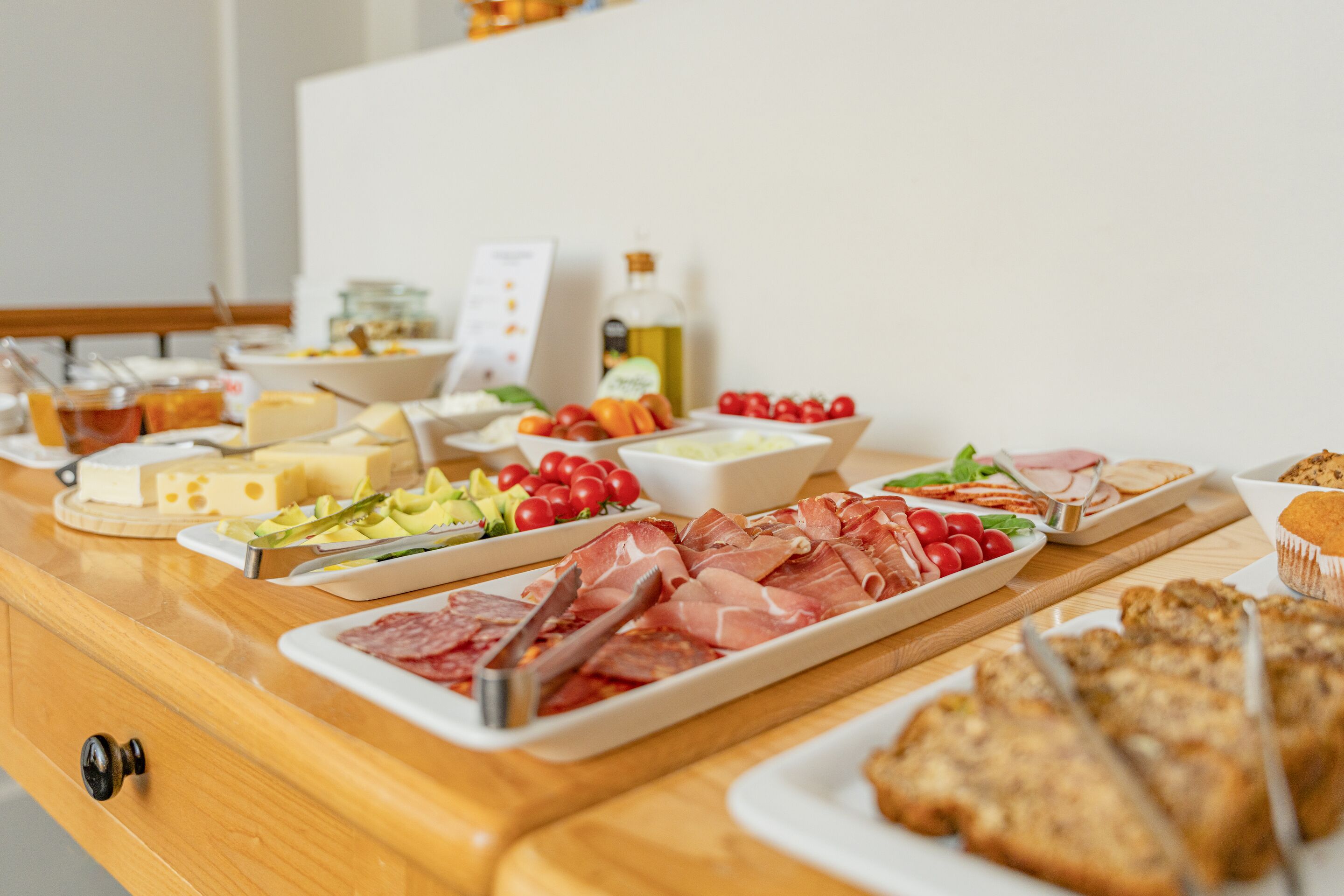 Una mesa de buffet con diversos alimentos, incluyendo carnes, quesos y verduras.