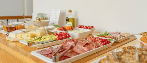 Una mesa de buffet con diversos alimentos, incluyendo carnes, quesos y verduras.