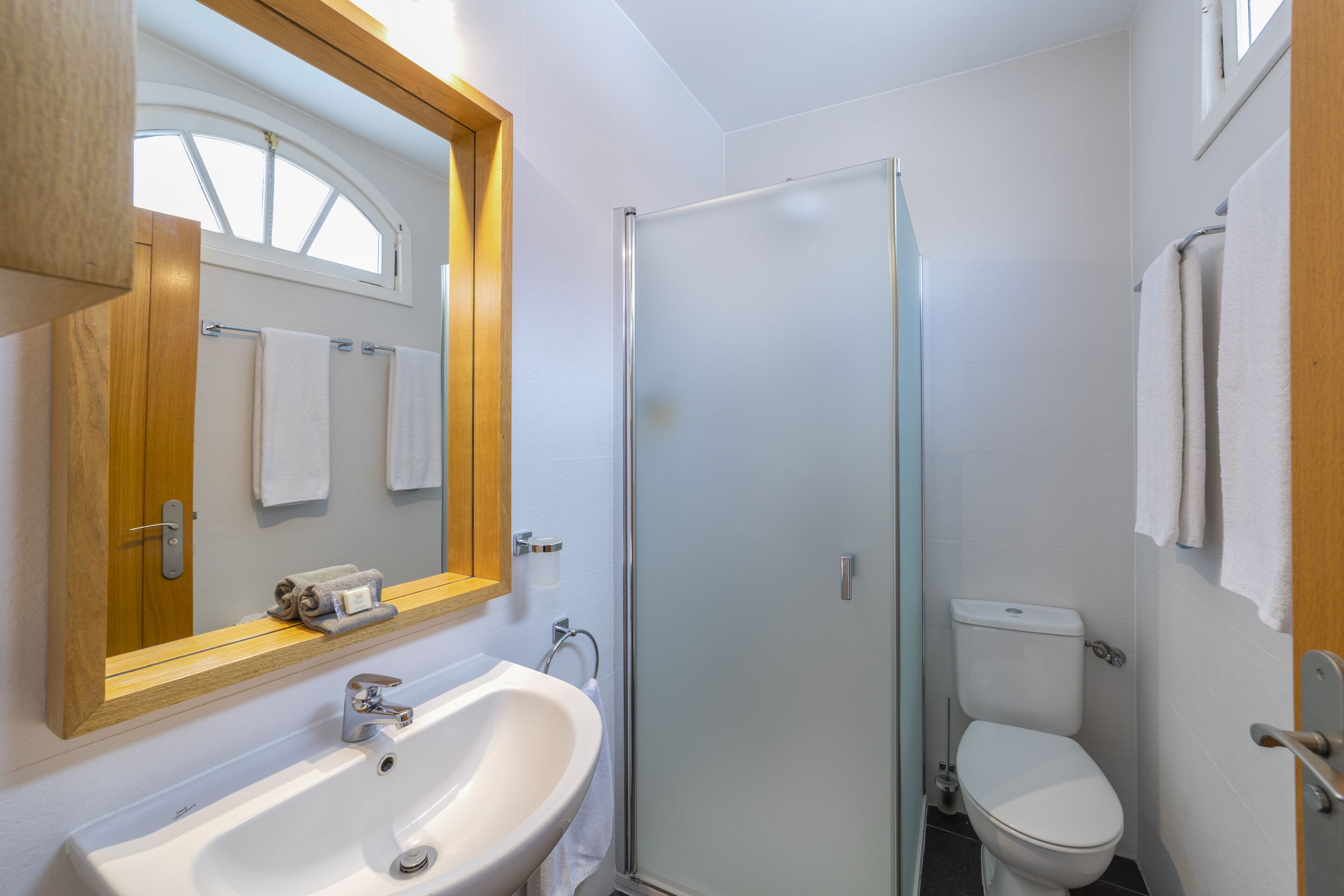 A bathroom with a white sink, a glass shower enclosure, and a white toilet.