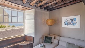 Een knus ingerichte kamer met een groot raam, een comfortabele bank, een sofa en een hangende lamp.