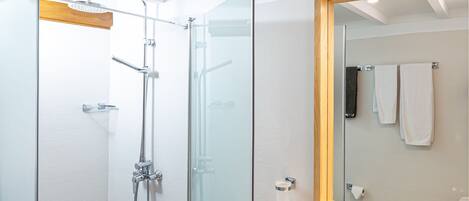 A modern bathroom with a glass-enclosed shower, a white sink, and a mirror with a wooden frame.