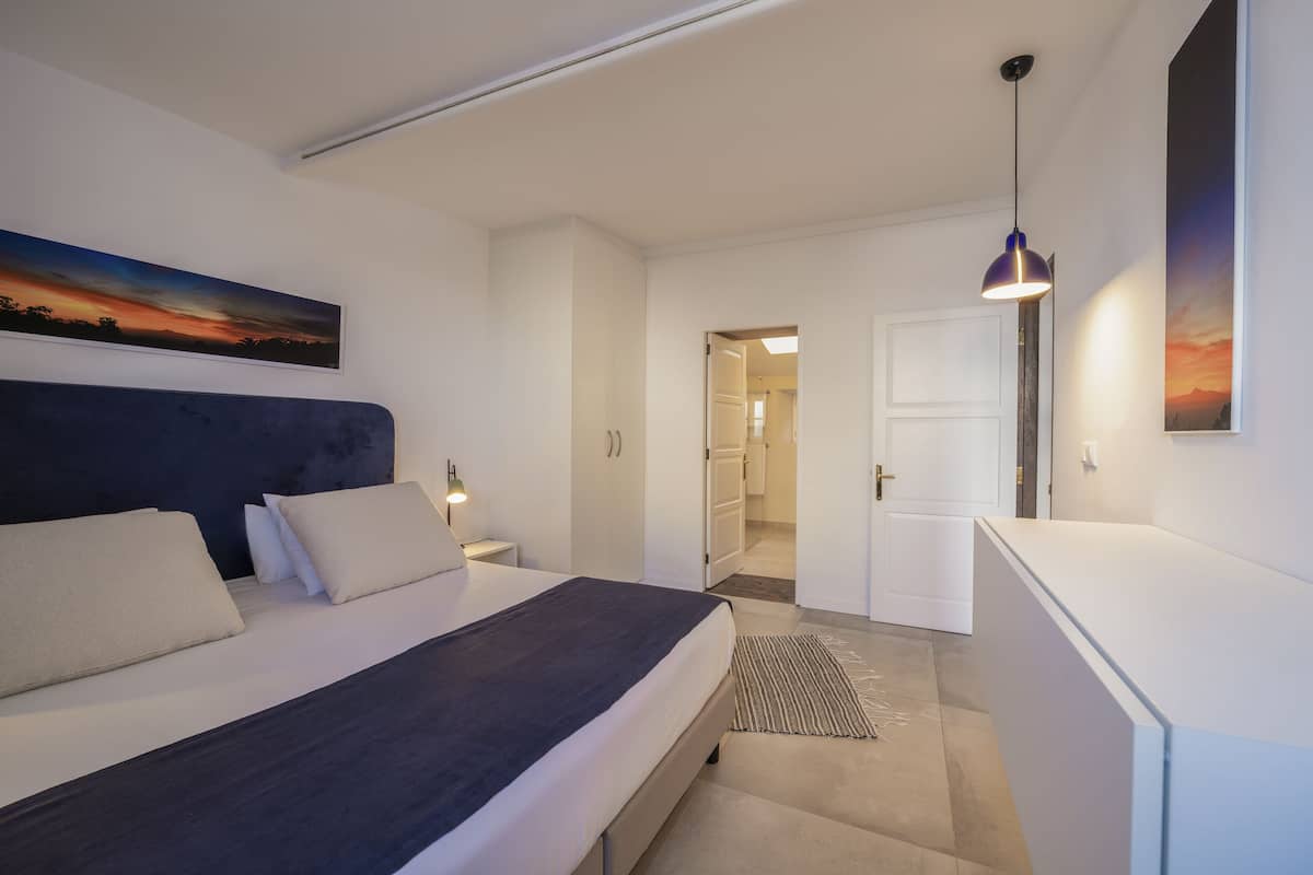Een slaapkamer met een bed, nachtkastjes, een bureau en een stoel.