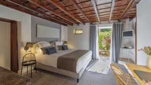 Een slaapkamer met een groot bed, een bureau met stoel, een televisie en uitzicht op de omgeving.