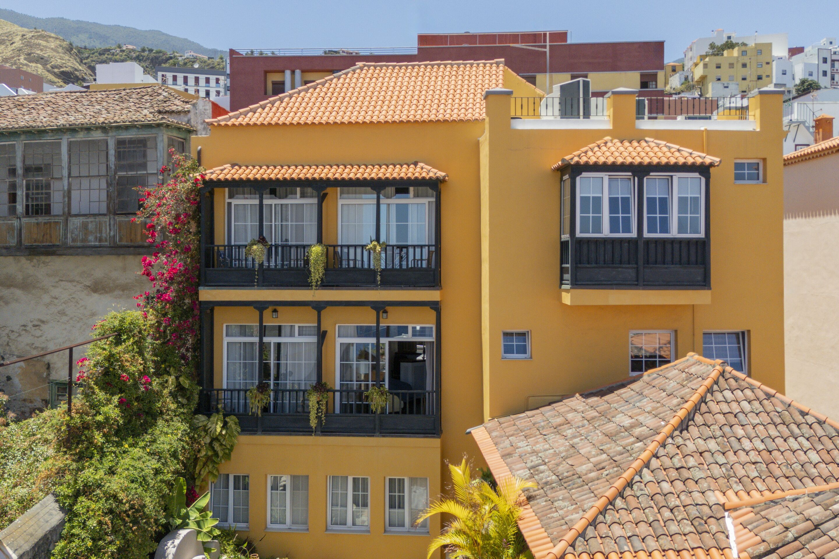 A yellow building with a tiled roof and balconies.