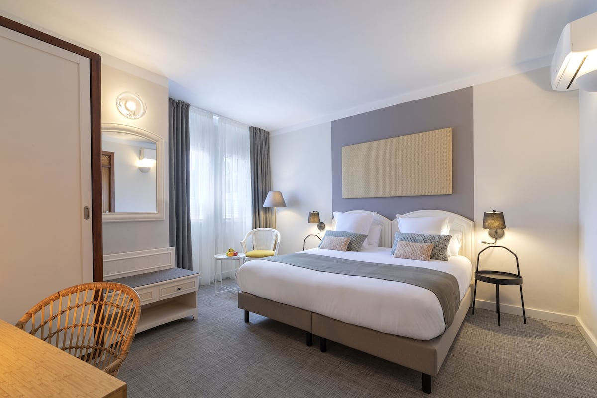 Een hotelkamer met een groot bed, nachtkastjes, een stoel, een bureau en een spiegel.