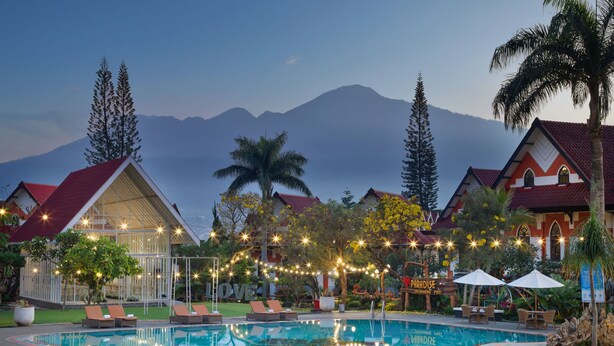 A pool area with lounge chairs, a swimming pool, and a view of mountains in the background. - Royal Hotel and Villa Batu (Batu)