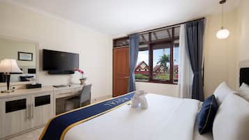 Habitación de hotel con cama, escritorio, silla, televisor y ventana con cortinas.