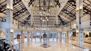 A spacious lobby with a high ceiling, chandeliers, and a reception desk. - Royal Hotel and Villa Batu (Batu)