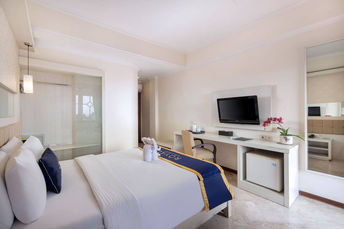 Une chambre d’hôtel comprenant un lit, un bureau avec un ordinateur, une télévision et un petit placard.