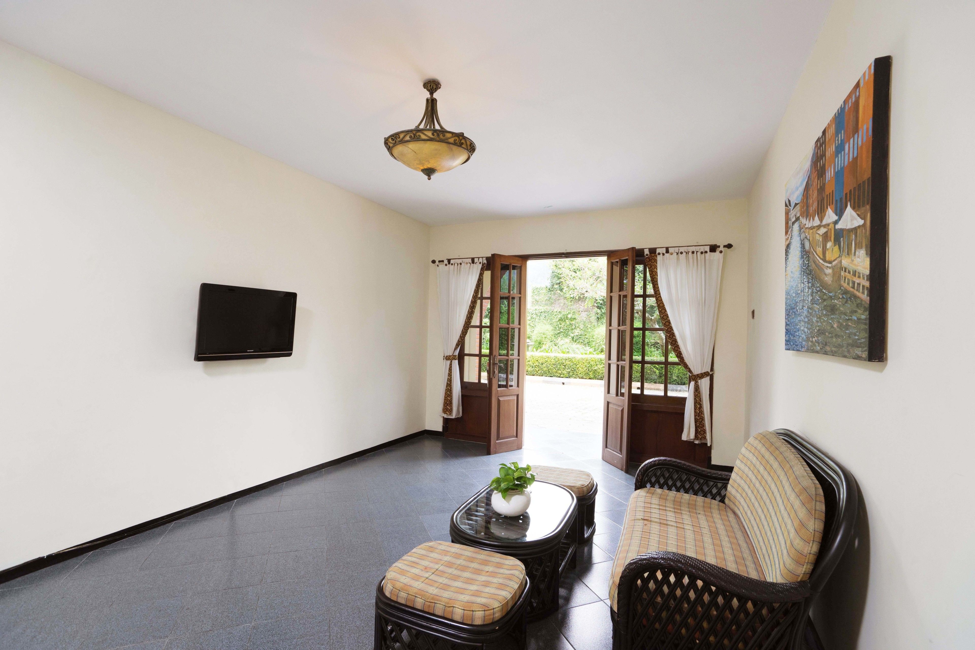 A room with a sofa, a small table with a plant, a flat-screen TV, and a painting on the wall.