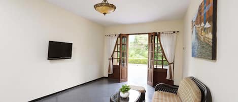 Una habitación con un sofá, una mesita con una planta, un televisor de pantalla plana y un cuadro en la pared.