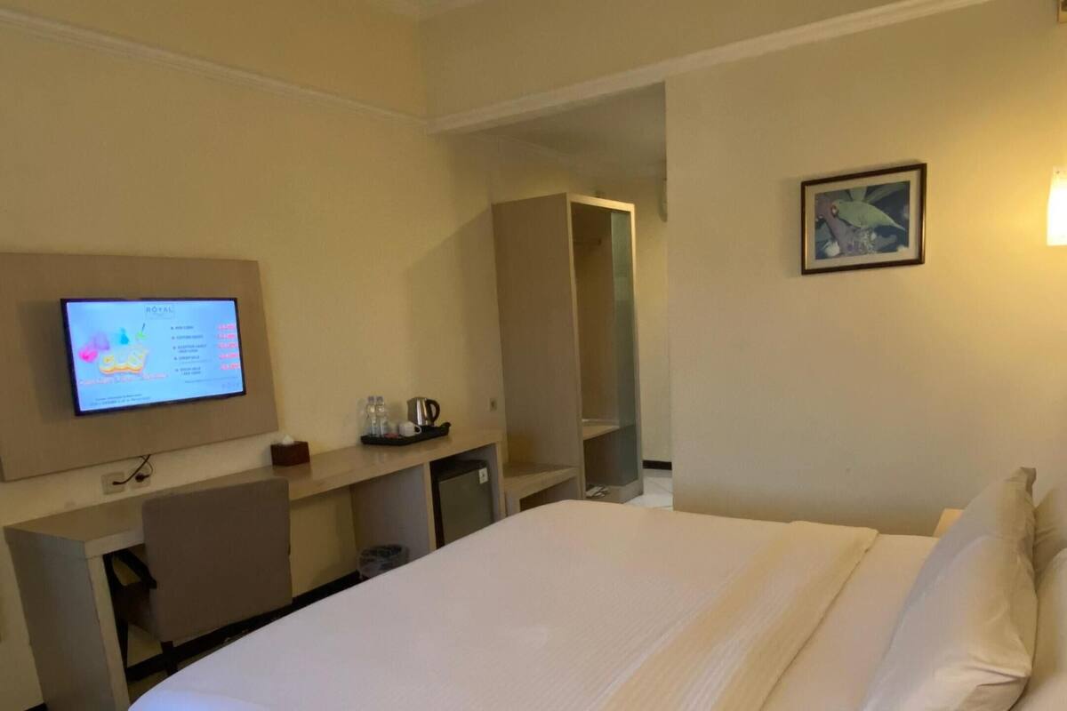 Une chambre d’hôtel avec un lit, un bureau, une télévision et une salle de bain, le tout visible à travers une porte ouverte.