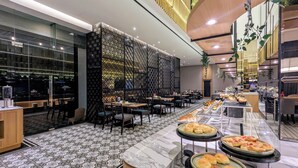 Een modern restaurant met een lange toonbank vol gebak, een patroon vloer en een decoratieve wand.