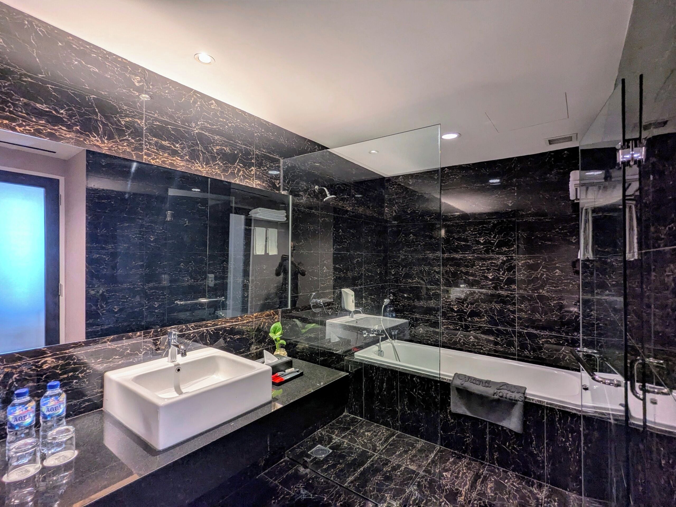 A modern bathroom with a large mirror, a bathtub, and a sink.