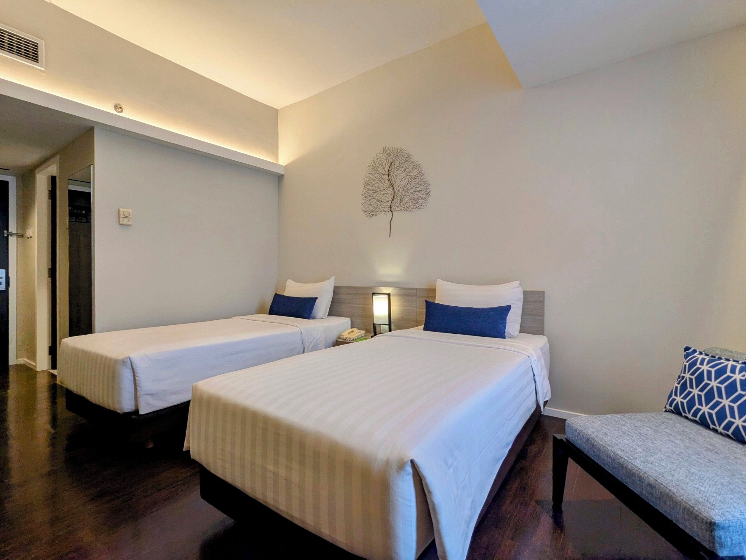 A hotel room with two beds, a small seating area, and a decorative wall piece.