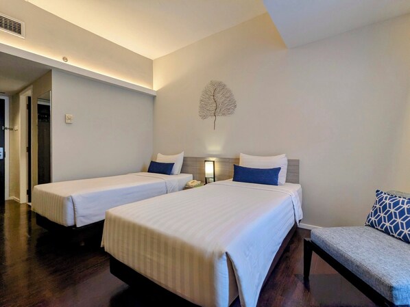 Habitación de hotel con dos camas, una zona de estar pequeña y un adorno en la pared.