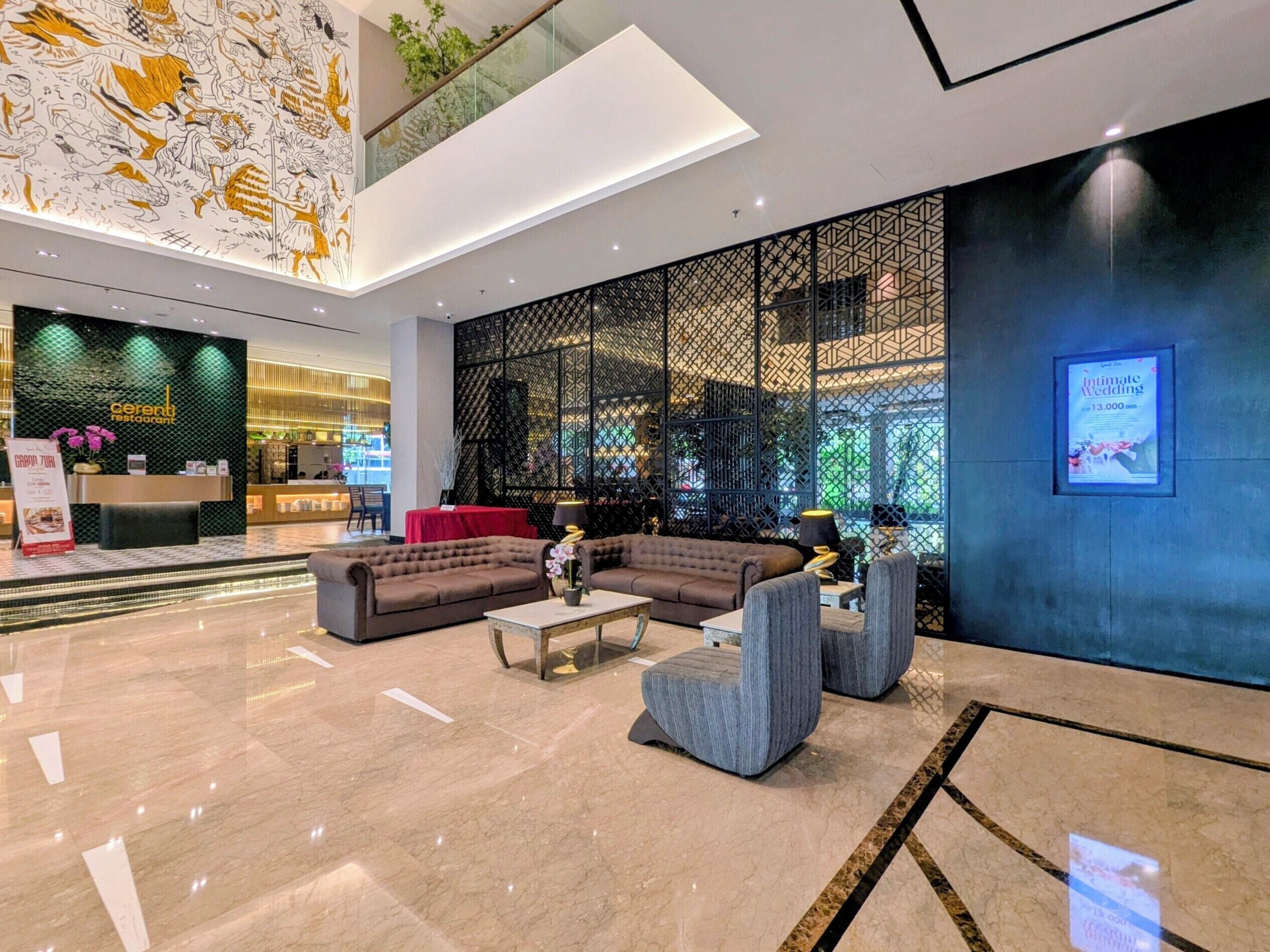A modern hotel lobby with a reception desk, seating area, and a decorative wall with a geometric pattern.