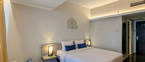 Habitación de hotel con una cama grande, una mesita de noche con lámpara, una silla y una obra de arte en la pared.