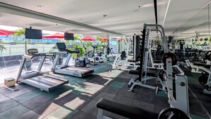Een sportschool met loopbanden, krachttoestellen en een spiegelwand.