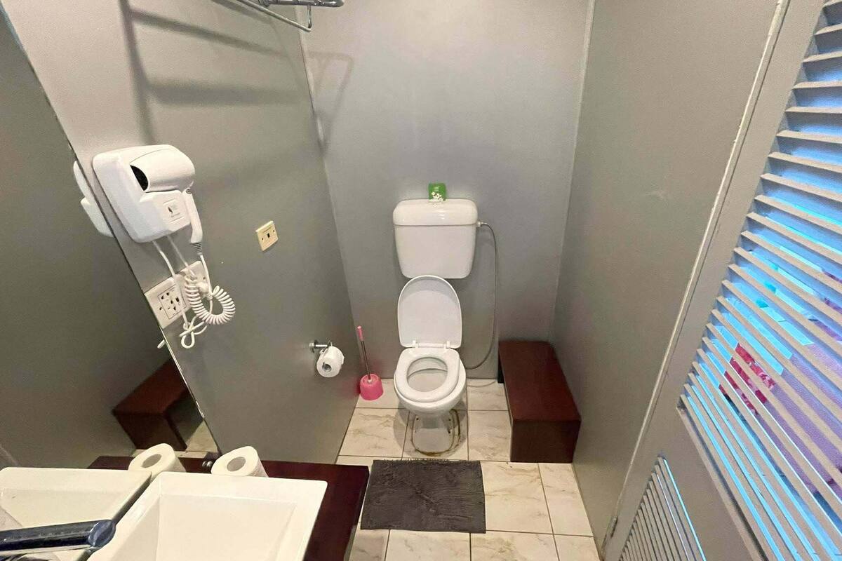 A small bathroom with a toilet, a hand dryer, and a sink.