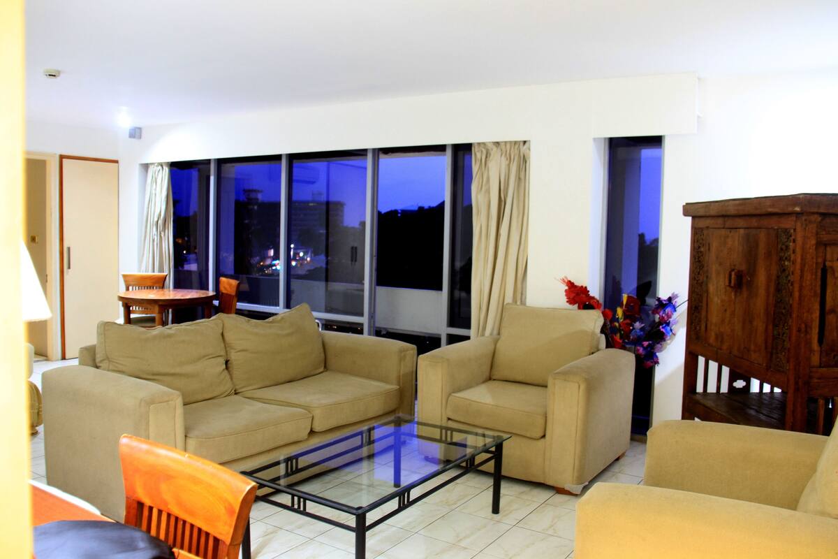 A living room with two beige sofas, a glass coffee table, and a wooden cabinet.