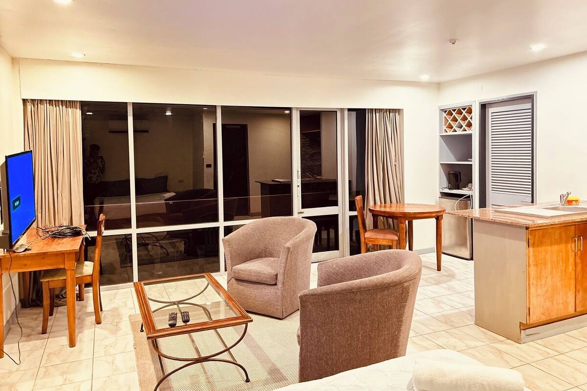 A modern living room with a television, a glass coffee table, and seating.
