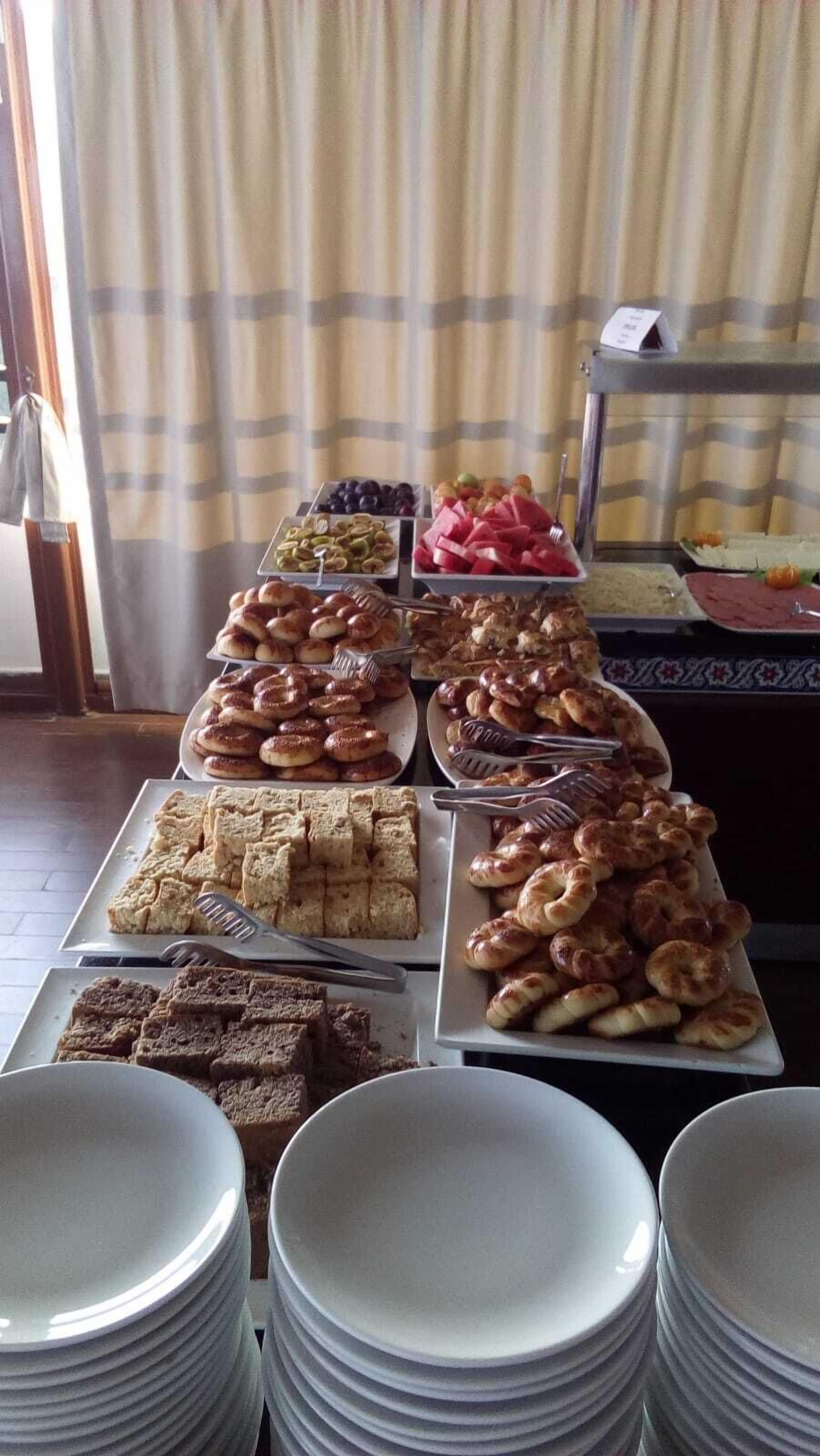 A buffet table with various food items and plates.