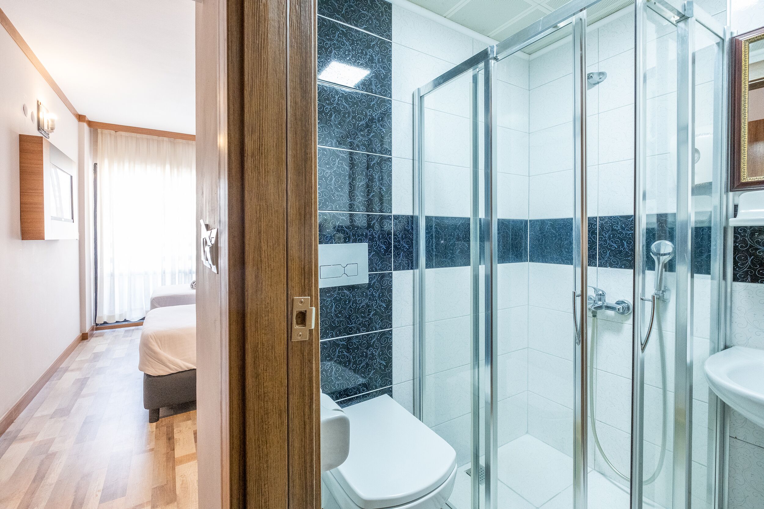 A hotel bathroom with a glass-enclosed shower, a white sink, and a toilet.
