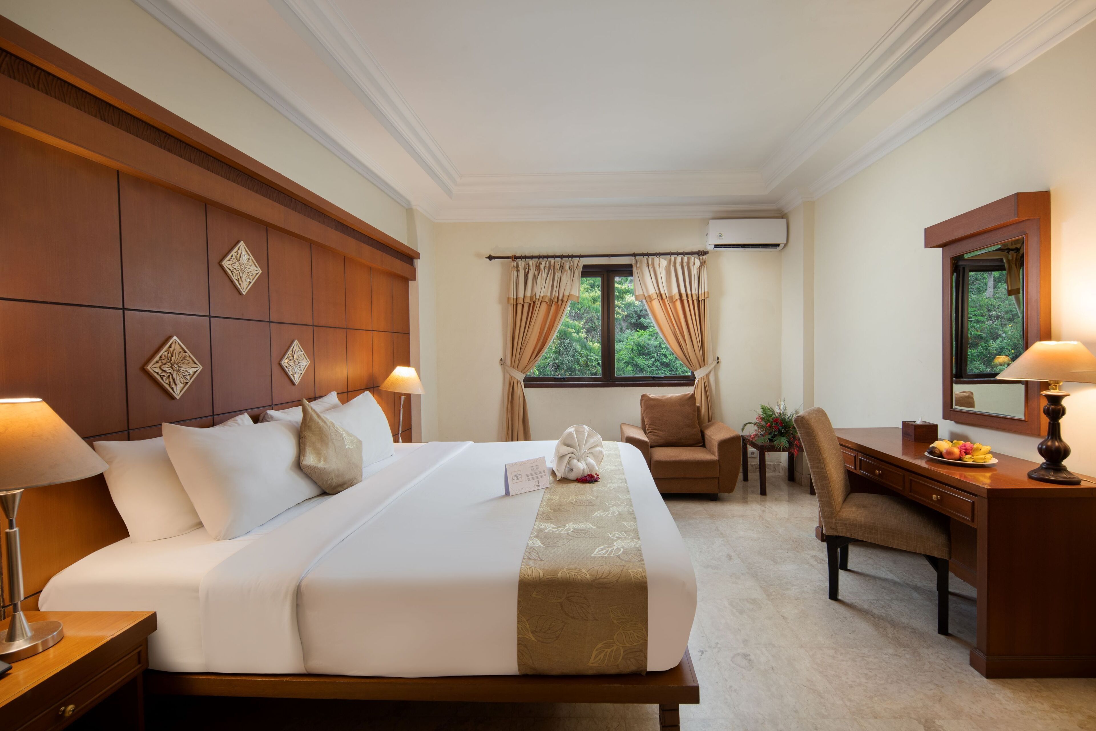 A hotel room with a large bed, a desk, a chair, and a window with curtains.
