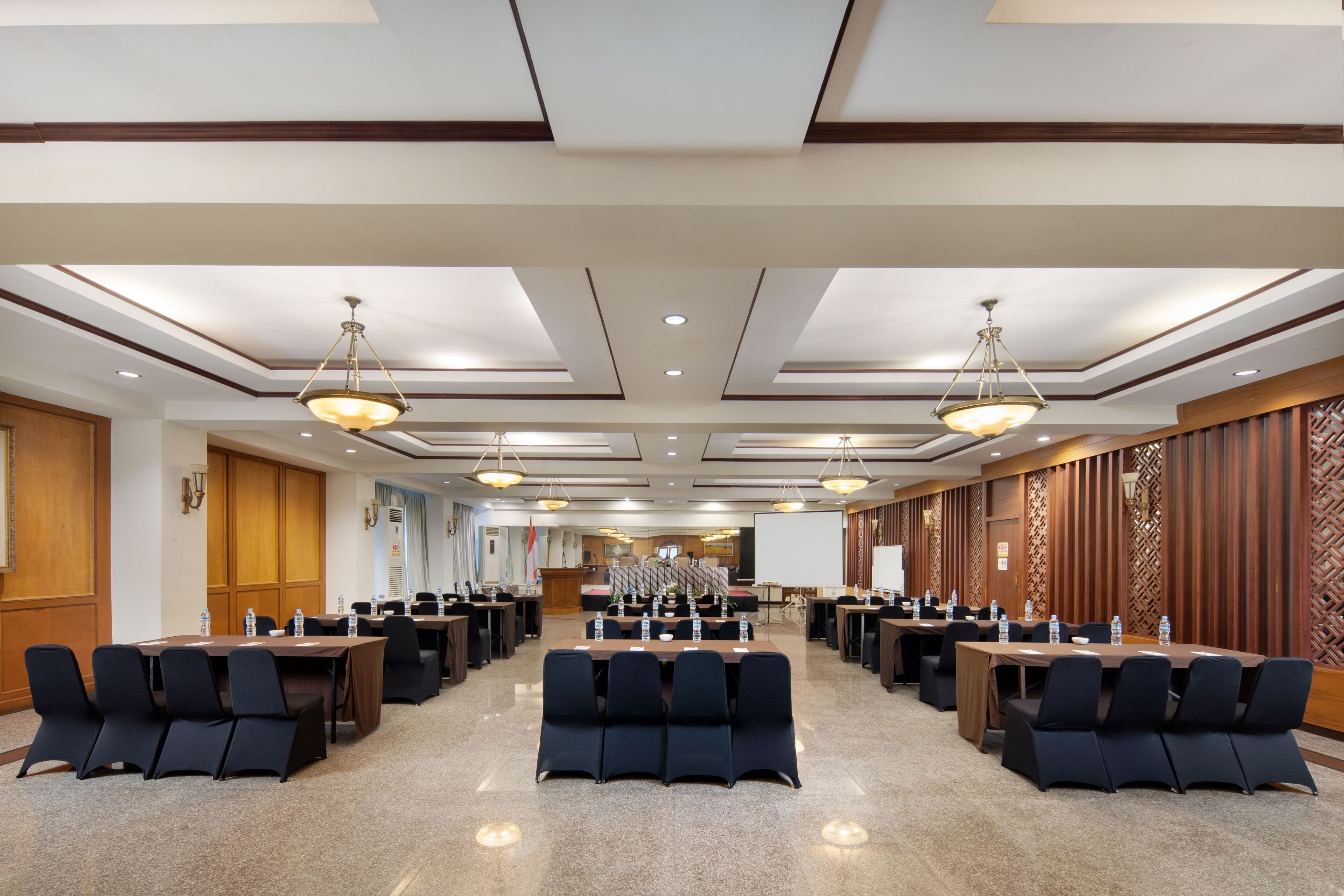A conference room with multiple tables and chairs, equipped with water bottles and nameplates.