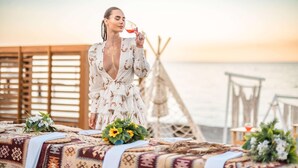A person sitting at a table with a patterned tablecloth, a glass of red wine, and a floral arrangement. - Sherwood Exclusive Kemer (Kemer)