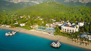 An aerial view of a coastal resort with a beach, villas, and a marina. - Sherwood Exclusive Kemer (Kemer)