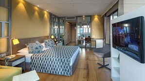 Habitación de hotel moderna con una cama grande, un escritorio, un televisor y un baño a la vista a través de una puerta abierta.