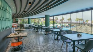 Un restaurante moderno con piso estampado, ventanas amplias y vista a una piscina.