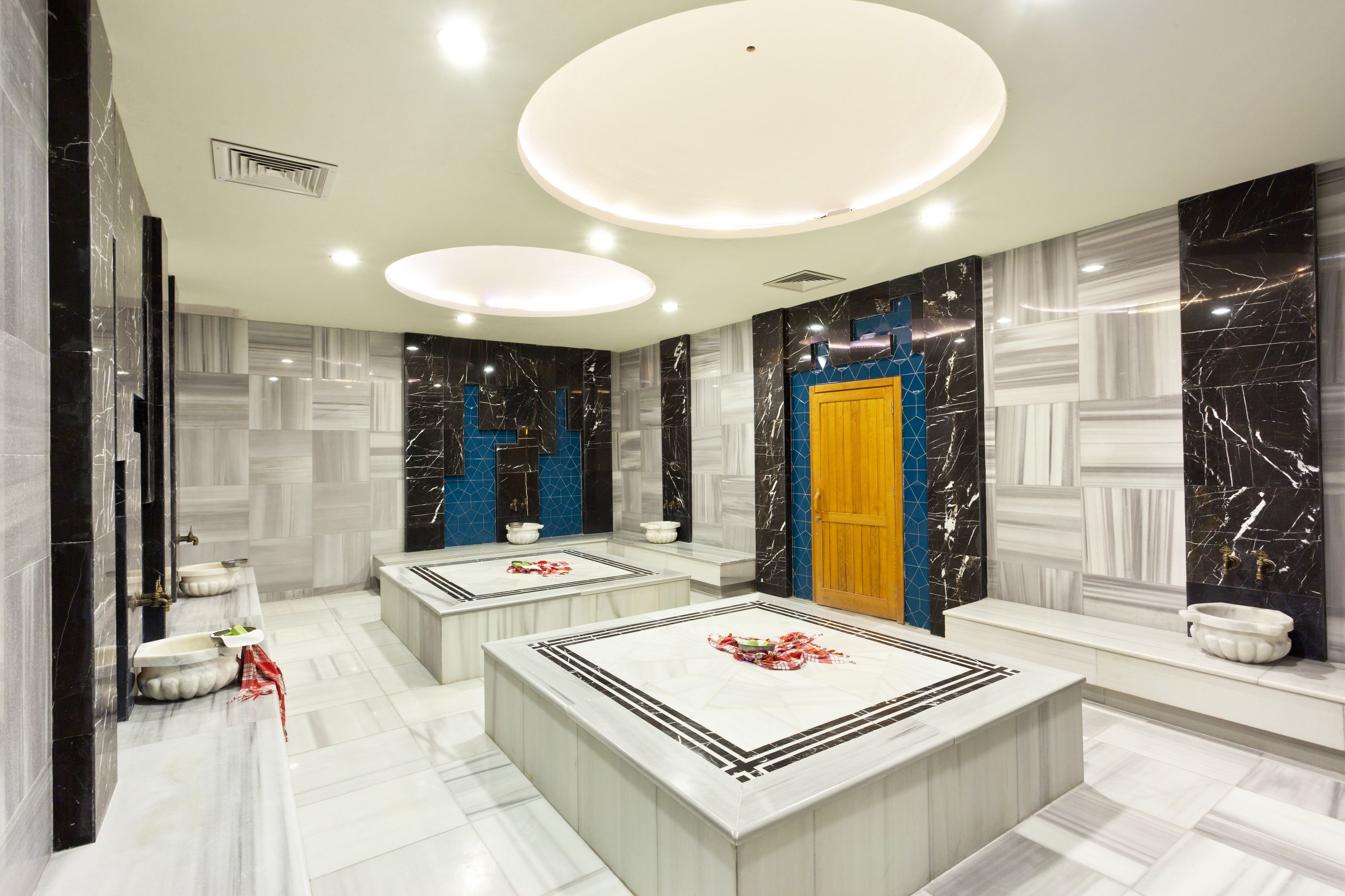 A modern bathroom with marble floors, a central sink, and a vanity with a mirror.