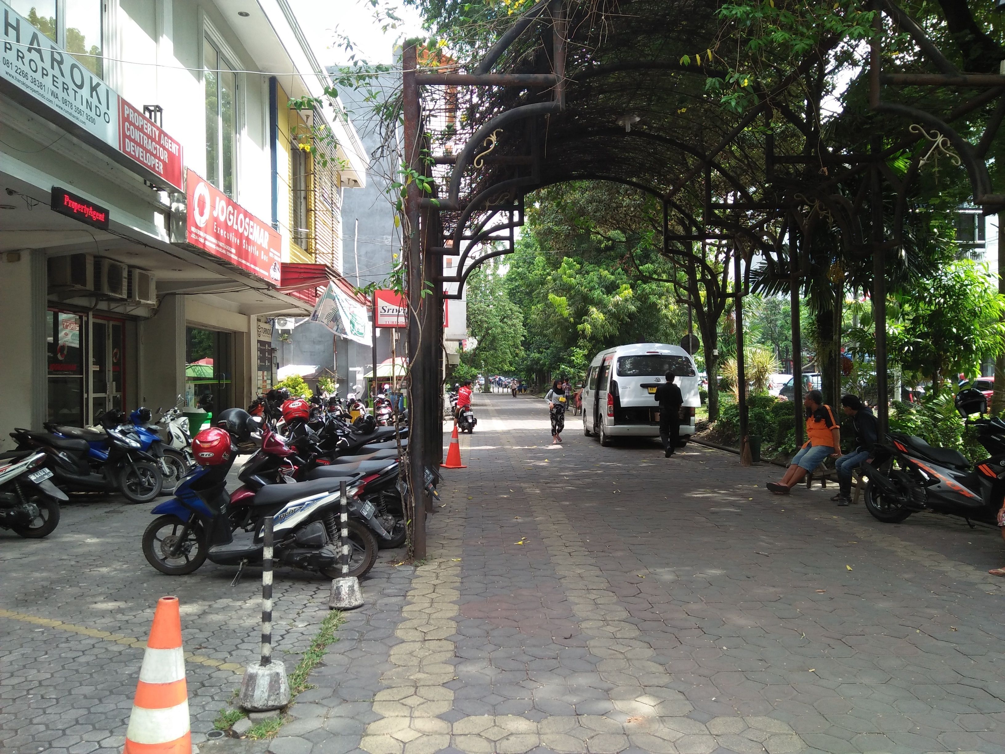 A street lined with parked motorcycles and a white van.